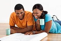man and woman drinking coffee and reviewing blueprints