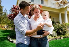 family with new baby in front of home