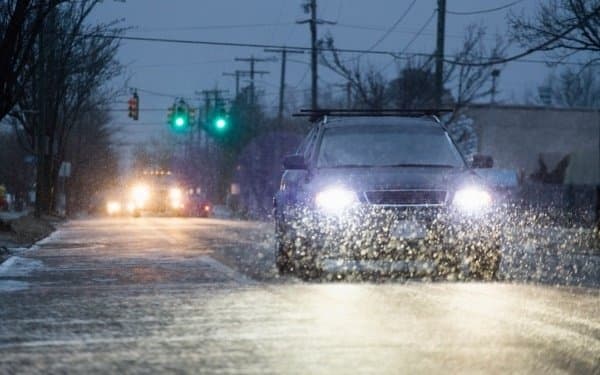 Car driving towards you, down the street, with headlights on.