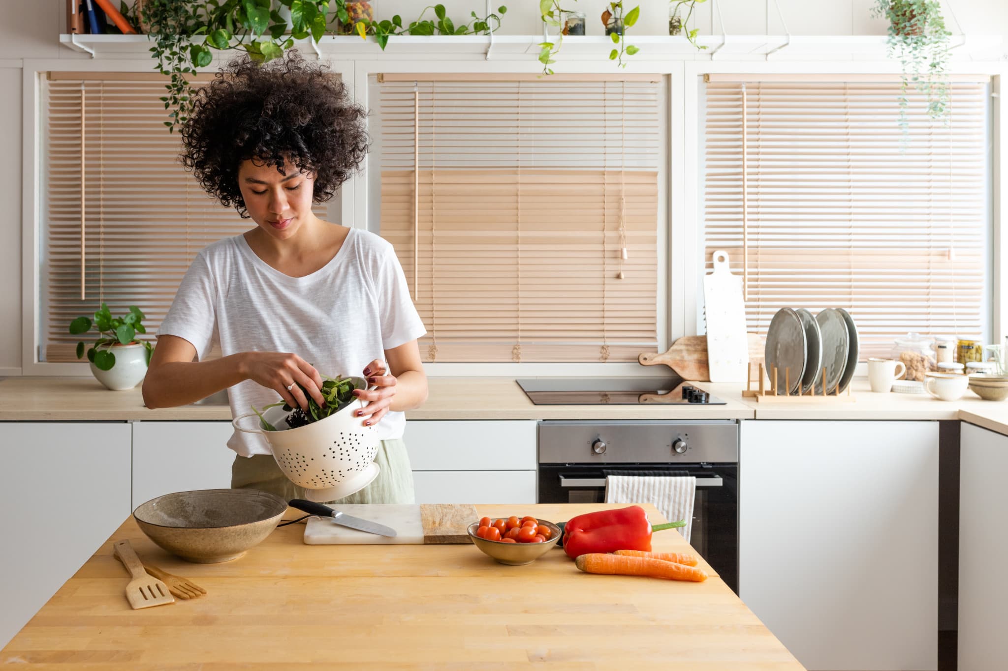 Women preparing a salad in a bright apartment kitchen, used to illustrate average renters insurance cost page.
