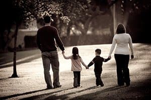 A family walking down the street holding hands.