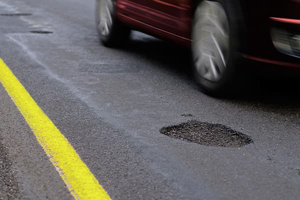 A car driving next to several potholes in a street.