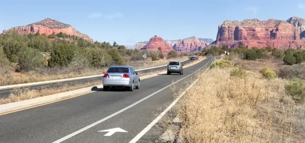 cars driving on an Arizona desert highway with red rock scenery, representing Arizona car insurance needs