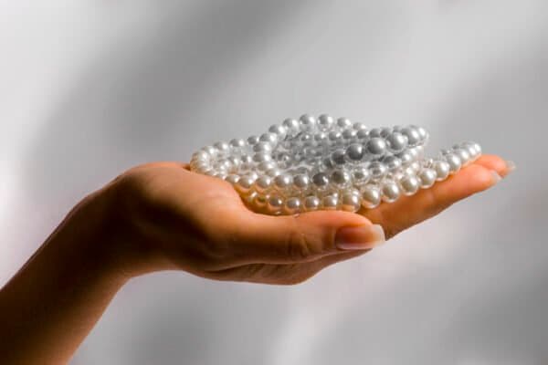 Woman's hand holding several pearl necklaces.