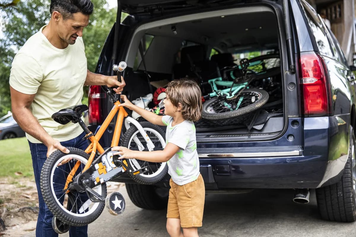 Parent and child loading a bicycle into an SUV