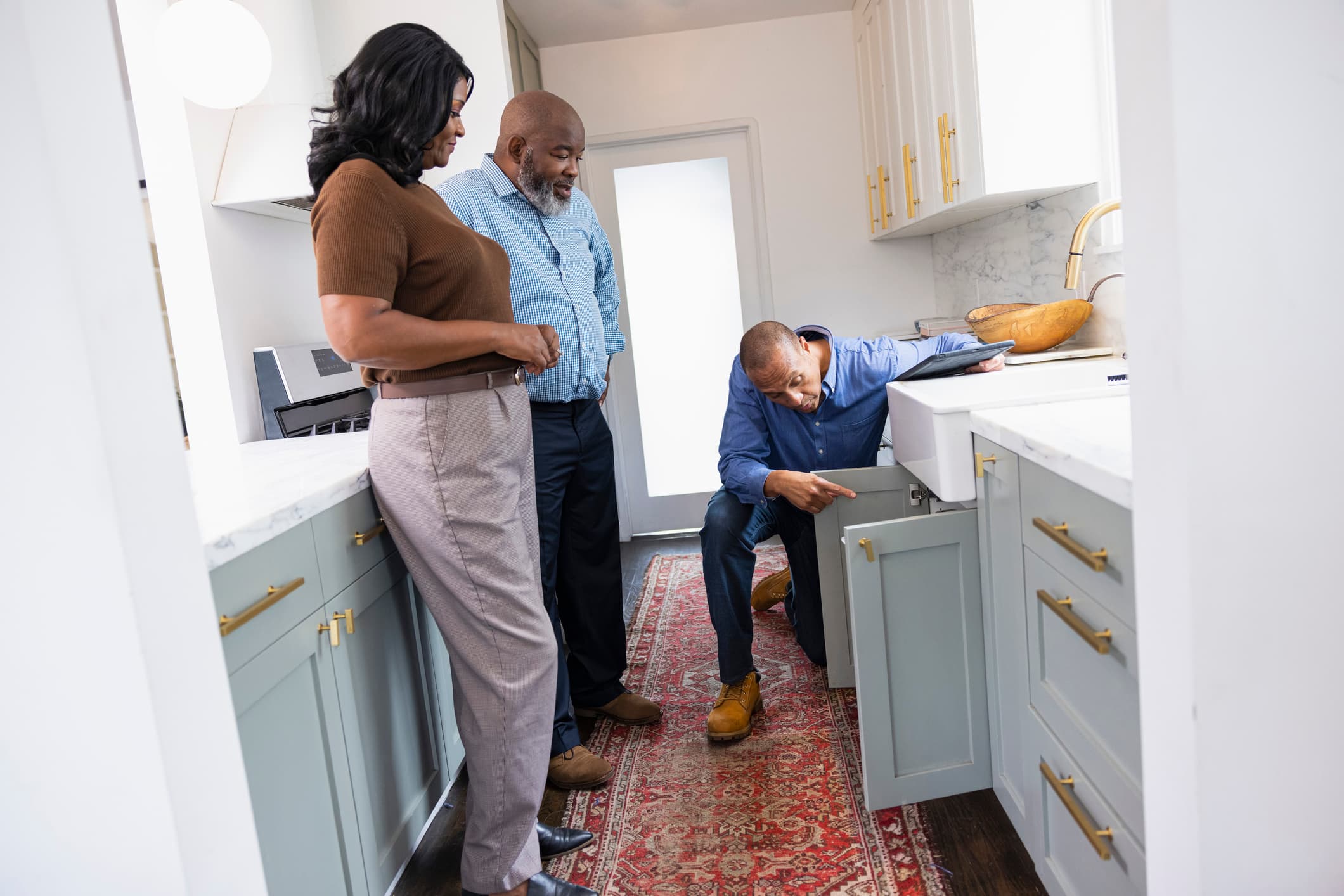 Home inspector examining a kitchen cabinet during an active homeowners insurance claim.