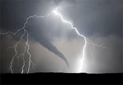 Viewing a tornado from far away with lightning striking the ground.