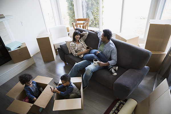 Moving boxes surrounding family relaxing in living room