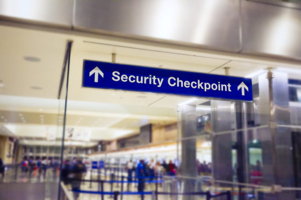 Airport Sign at the entrance of the security checkpoint with People waiting in line.