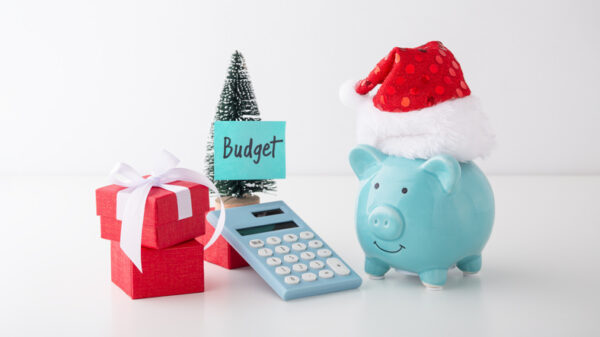 Christmas budget and saving concept, piggy bank with christmas hat, decoration and calculator on white table