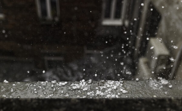 Hail smashing on window sill during hailstorm