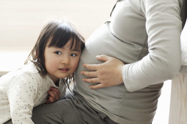 Little girl listening to pregnant mother's abdomen