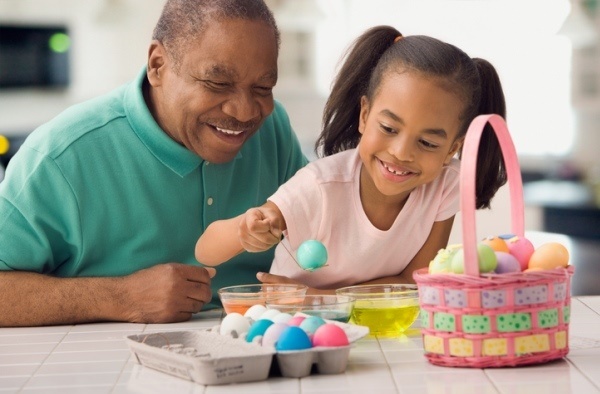 african american grandfather and granddaughter dyeing Easter eggs