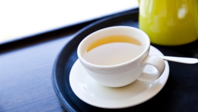 Cup of Green Tea on a tray with saucer and spoon
