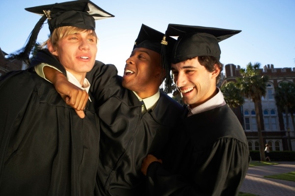 Young men in graduation cap and gowns embracing, close-up