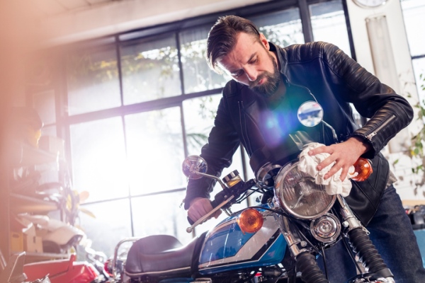 Male motorcycle mechanic wiping motorcycle in workshop
