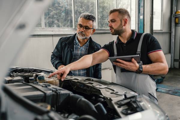 Two men looking under the hood of a vehicle
