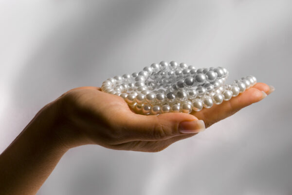 Woman's hand holding several pearl necklaces.