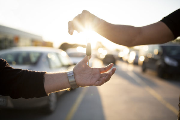 A man handing his car key over to another man to let him borrow his vehicle.
