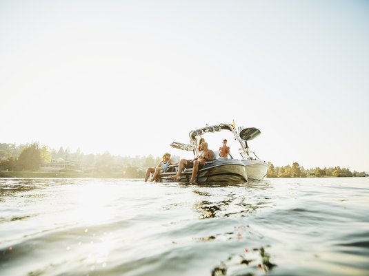 Family sitting on their boat while it floats in the middle of a lake.