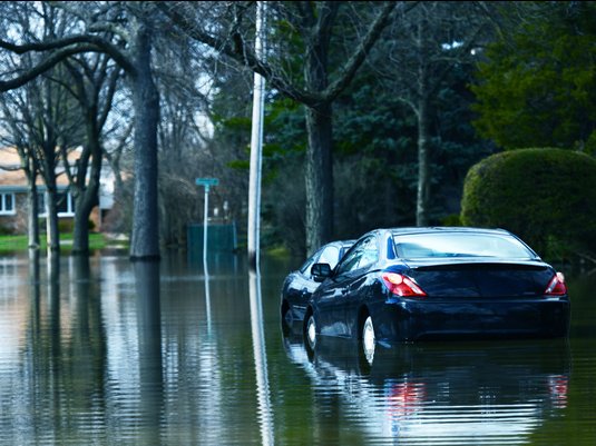 Car parked on a flooded residential street.