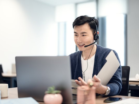 Insurance agent talking to customer on his headset while sitting at his desk.