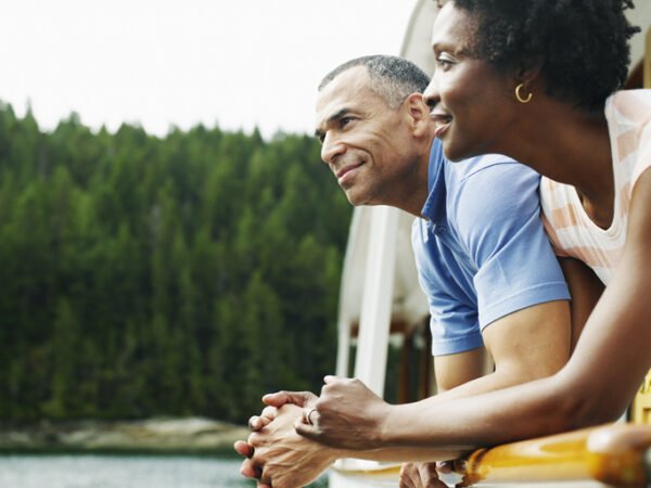 A couple leaning against a railing and smiling.