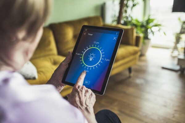 Older woman using a smart app to program the lights in her home.