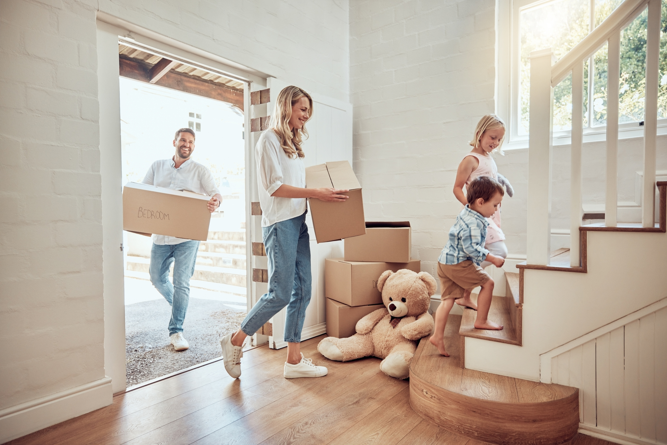 Family carrying moving boxes into their first home together.
