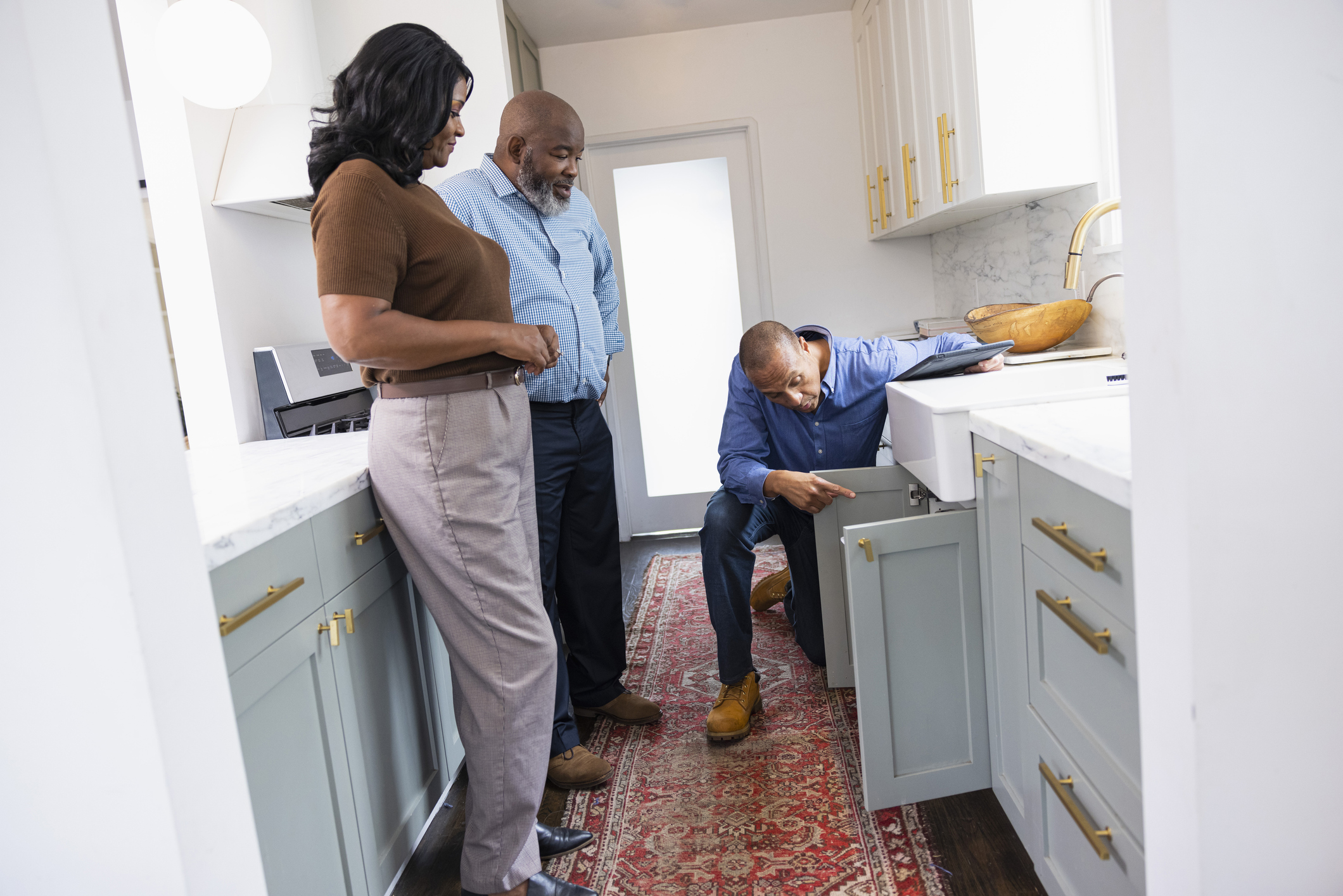 Home inspector examining a kitchen cabinet during an active homeowners insurance claim.