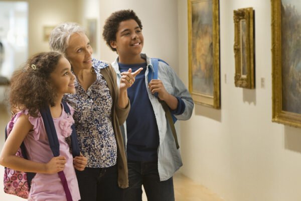 Kids visiting an art museum with their grandma and talking about a painting on the wall.