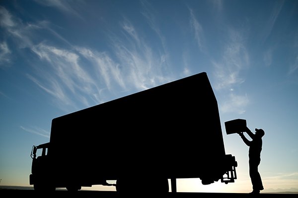 Silhouette of a man removing a box from a moving truck.