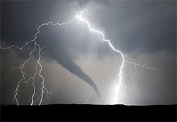 Viewing a tornado from far away with lightning striking the ground.