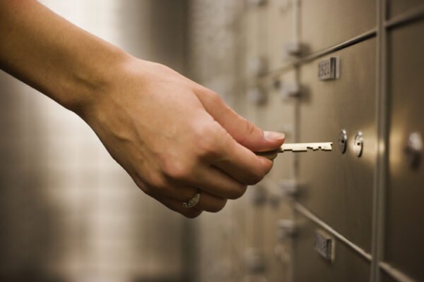 A person opening a safe deposit box with a key.