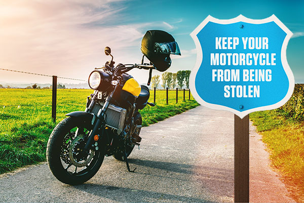 Motorcycle parked on a country road next to a sign that reads: KEEP YOUR MOTORCYCLE FROM BEING STOLEN