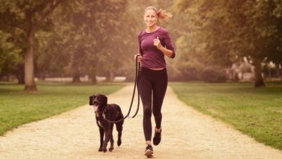Woman out for a jog in a park with her dog.