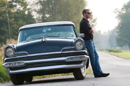 Man leans against old car