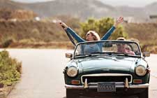 retired couple driving convertible