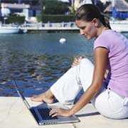 woman using a laptop by a lake