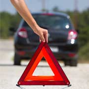 Someone placing road hazard sign in front of disabled vehicle while waiting for GEICO Emergency Roadside Service