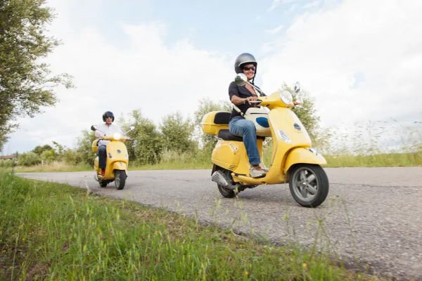 A couple on scooters driving down the road